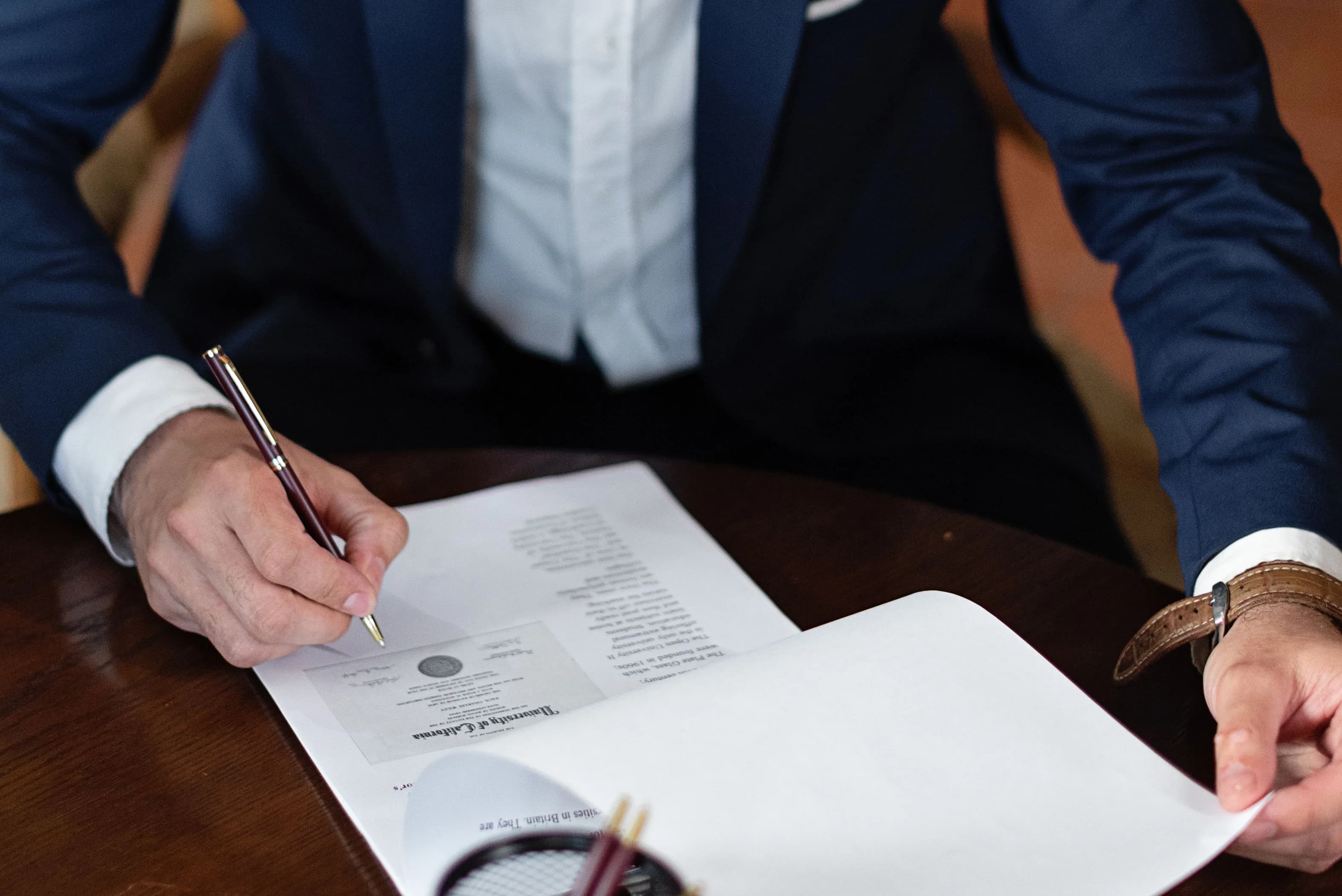 A professional signing official documents at a desk, representing the compliance paperwork stablecoin issuers face