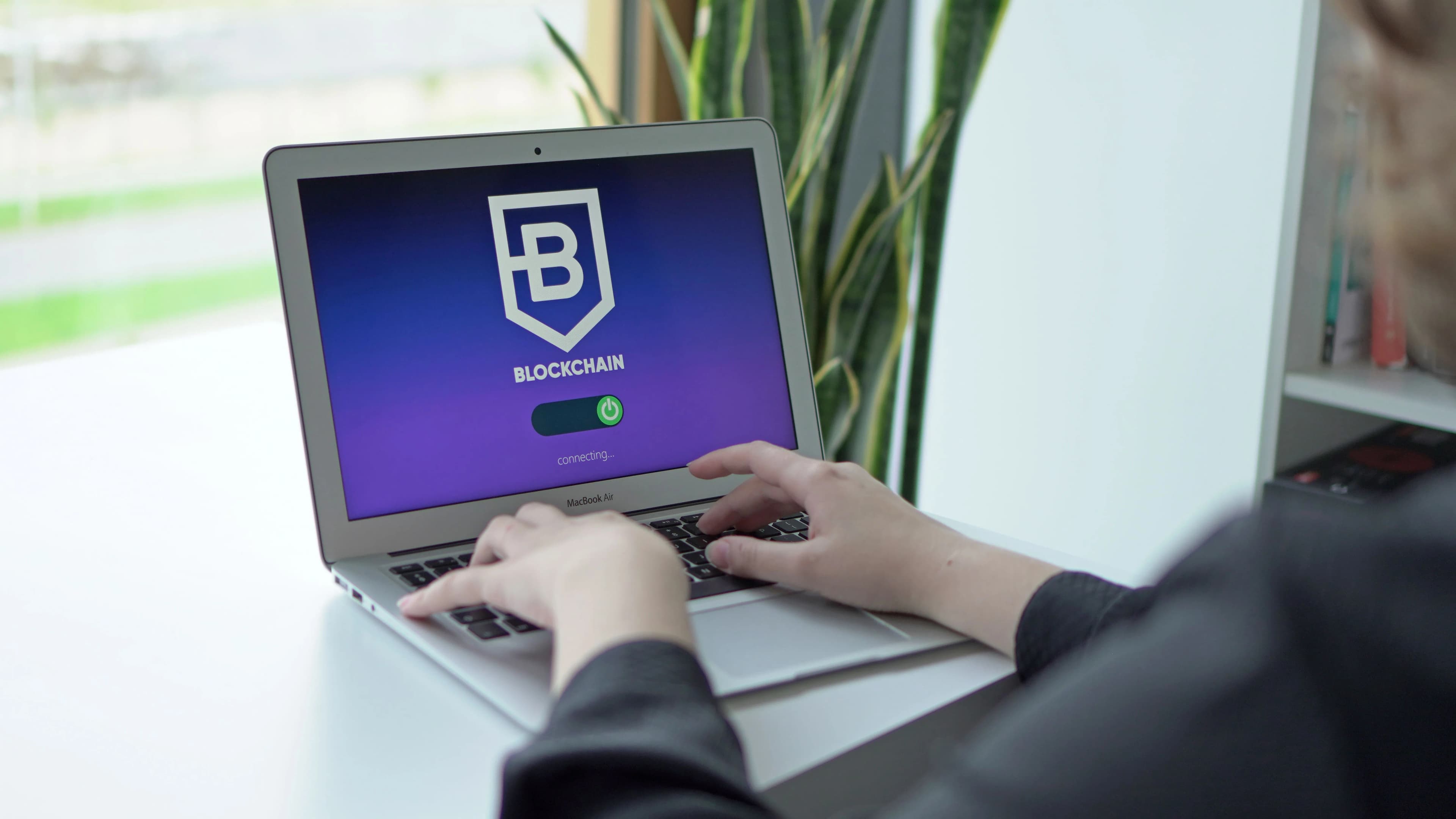 Hands using a laptop displaying a blockchain application interface