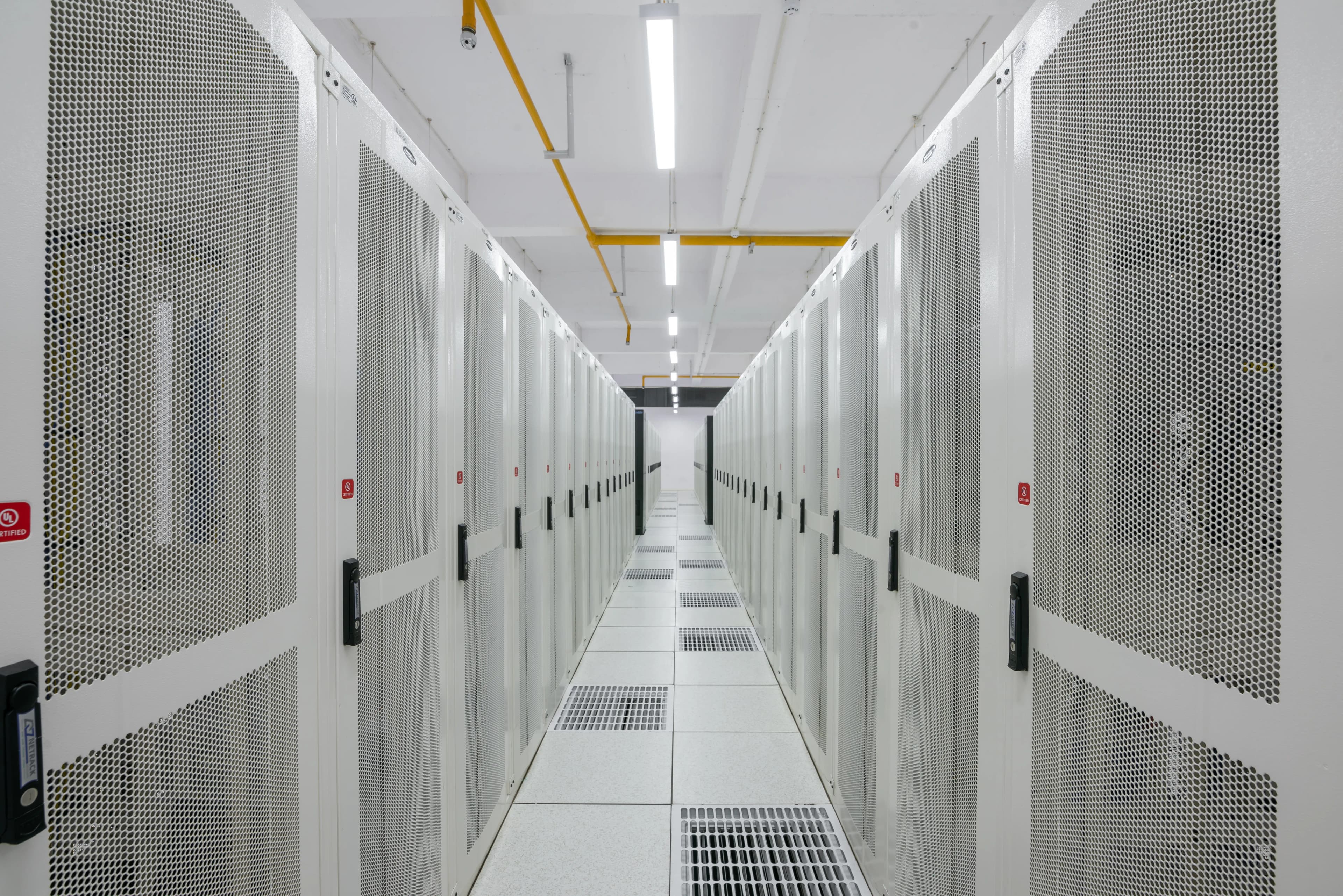 Rows of server racks inside a data center, representing the validator infrastructure processing Solana's onchain activity. Photo by PiDatacenters on Wikimedia Commons.